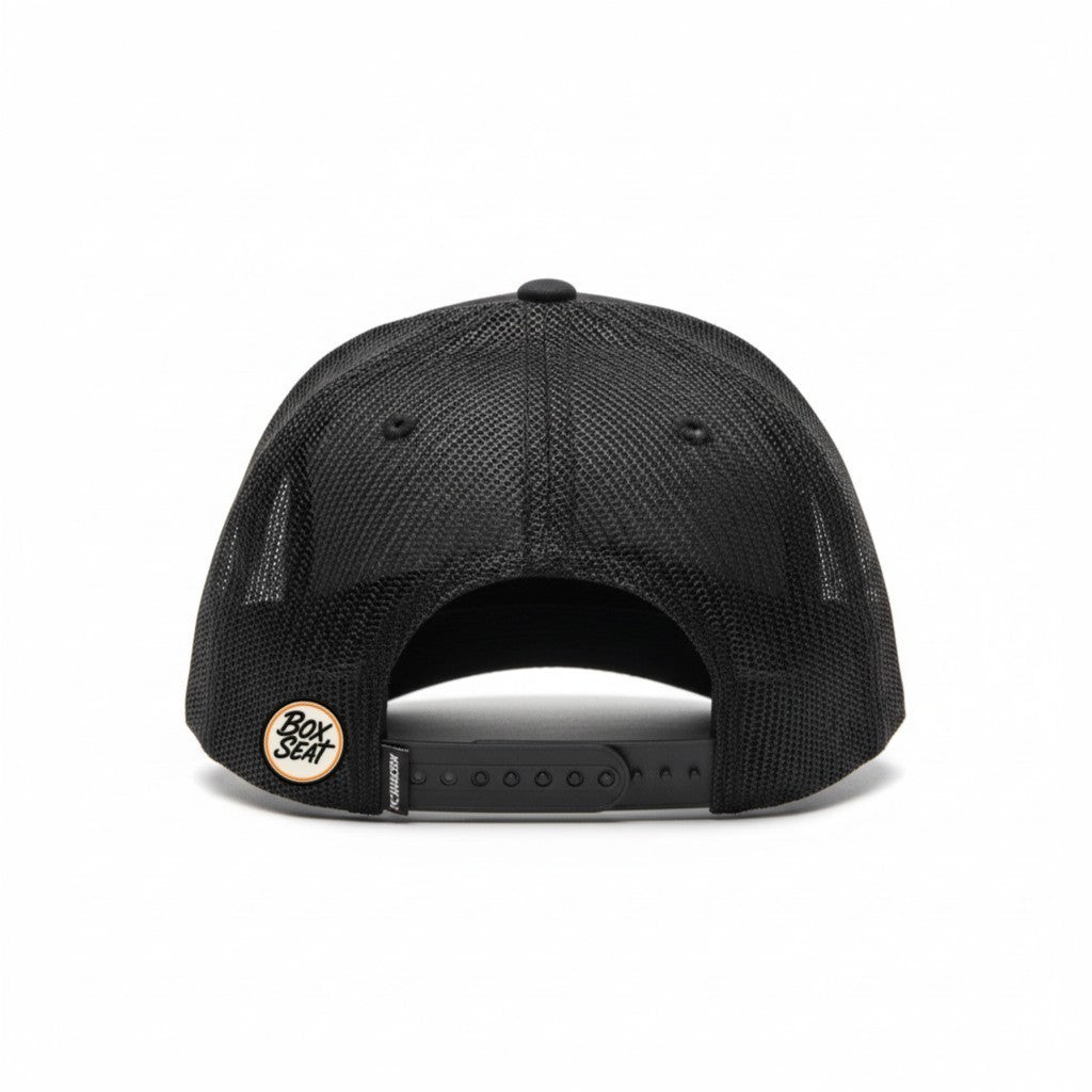 Rear view of a black BOX SEAT trucker hat with mesh back panels and an adjustable snapback closure.