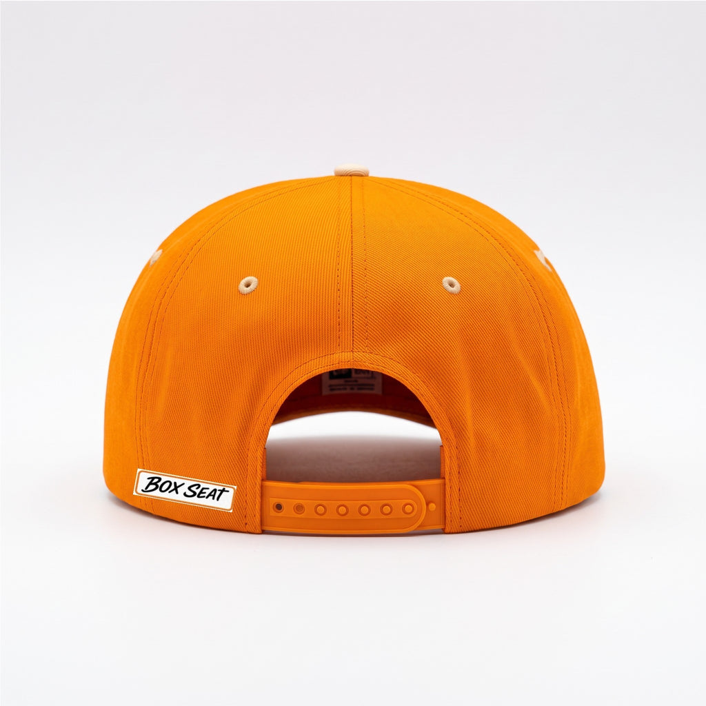 Back view of a bright orange BOX SEAT snapback hat with a white brand logo tag on the adjustable strap.